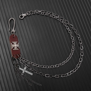 Détail d'une chaîne de pantalon punk vintage en métal avec pendentif croix et cuir