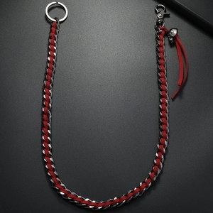 Détail d'une chaîne argent punk avec ruban rouge tressé et pendentif crâne