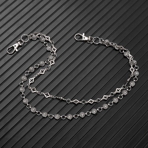Détail d'une chaîne de taille punk double couche avec charms arbre de vie et trèfle en métal