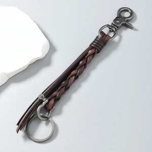 Detail of hand-woven dark brown leather keychain with vintage metallic horseshoe buckle
