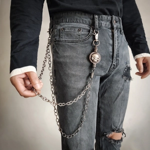 Detail of punk silver trouser chain with skull emblem and double-layer metal links