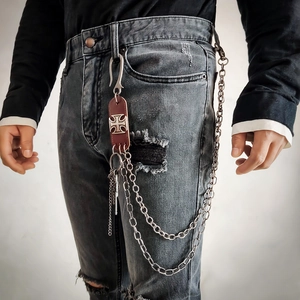 Détail d'une chaîne de taille hip-hop avec croix et cuir sur un jean vintage