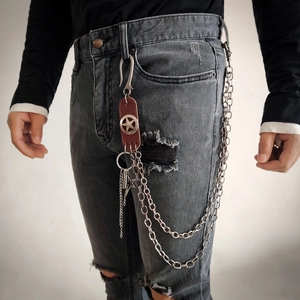 Detail of silver double layer chain pant accessory with leather star patch on denim