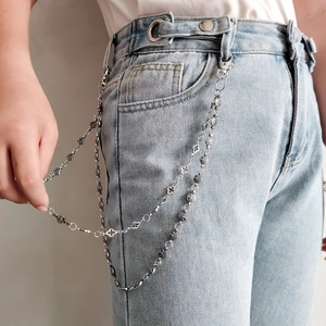 Détail d'une chaîne de pantalon double en métal argenté avec motifs croix sur jean