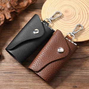 Vintage leather key cases in black and brown with metal hooks on a rustic wooden background
