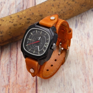 Detail of square quartz watch with orange leather strap wrapped on a wooden branch