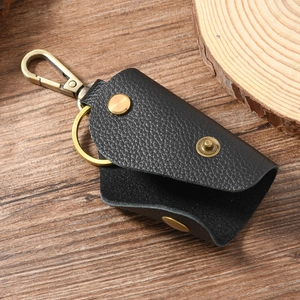Retro black pebble grain leather key case with bronze lobster clasp on wooden background