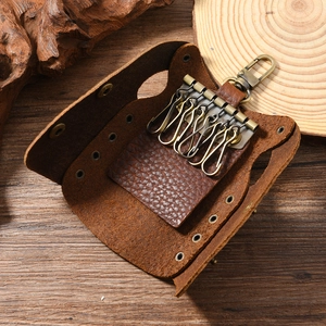 Detail of vintage leather key case featuring six hooks and bronze lobster clasp on wood