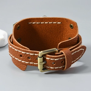 Detailed view of vintage brown leather wristband with white stitching and bronze buckle