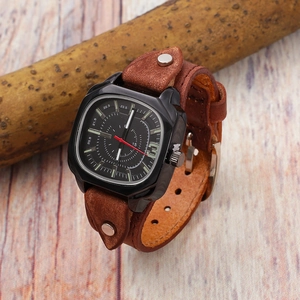 Detail of square black watch case with brown leather rivet strap on wood background
