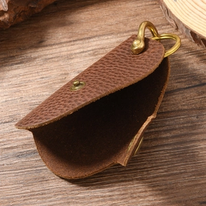 Vintage lychee grain leather key pouch with rustic brass hardware on wood background