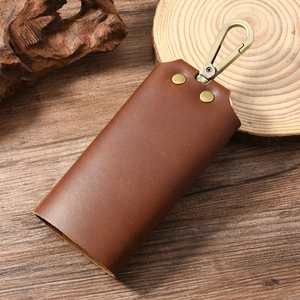 Macro detail of vintage brown leather key holder with brass spring buckle on wood