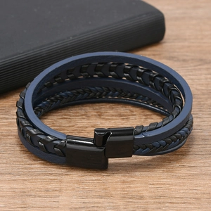 Détail d'un bracelet multicouche en cuir tressé pour homme avec fermoir magnétique sur bois
