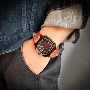 Retro square quartz watch with brown leather riveted strap on a male model's wrist