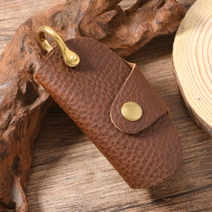 Detailed close-up of dark brown lychee grain leather key pouch with brass U-shaped hook