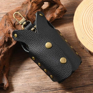 Detail of vintage black litchi grain leather key pouch with bronze rivets on wood background