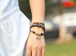 Detail of bohemian layered leather bracelets featuring colorful beads and a silver butterfly charm