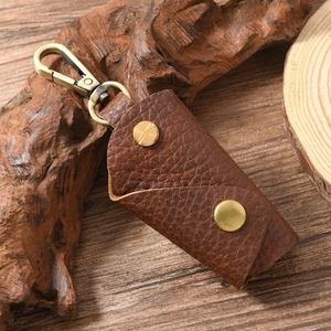 Close-up of brown litchi grain leather key pouch with vintage metal hardware and snap buttons