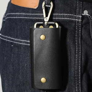 Litchi pattern leather key pouch with gold metal hooks hanging on blue denim jeans