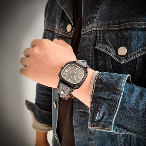 Close-up of retro square metal watch with dark leather strap and rivet detailing