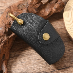 Detail of black lychee grain leather key pouch with brass snap and U-shaped hanger