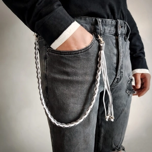 Hand-woven wax cord pant chain with metal lobster clasps and tassels on grey denim