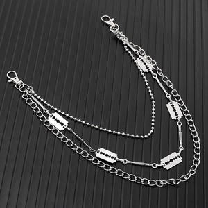 Three-layer punk chain belt with silver razor blade charms on a black striped surface