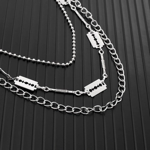 Detail of layered silver chain belt featuring edgy razor blade charms in punk street style