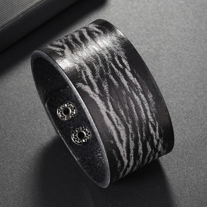 Detail of wide black leather bracelet featuring gray tiger stripe texture and metal snaps