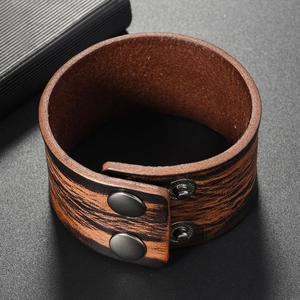 Macro view of wide vintage leather cuff bracelet with wood grain texture and metal snaps