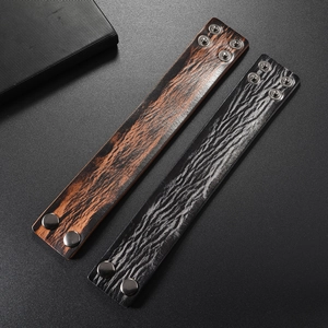 Detail of vintage leather bracelets featuring brown wood grain and black cracked texture