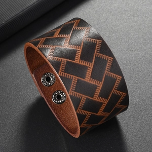 Detail of wide black leather bracelet featuring geometric embossing and dual silver snaps