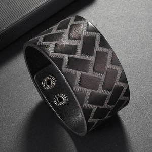 Detailed macro view of black wide leather bracelet with embossed geometric textures