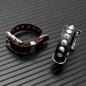 Dettaglio macro di bracciali punk in pelle con rivetti e stemma a croce metallica