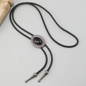Macro view of vintage western bolo tie featuring black gemstone and engraved metal tips