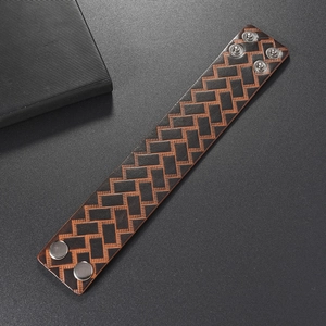 Macro detail of retro wide leather bracelet showing herringbone pattern and adjustable snaps