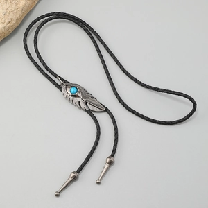 Detail of vintage feather bolo tie with turquoise stone and braided black leather cord