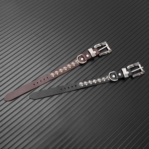 Dettaglio di bracciali punk in pelle con borchie coniche argentate e fibbia floreale