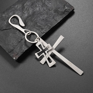 Minimalist double cross keychain with S-hook and silver pendants on stone background