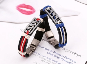 Detail of dolphin relief on couple's leather bracelets with red and blue woven ropes