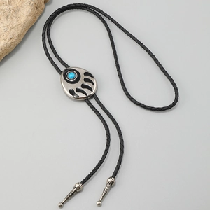 Detalle de corbata bolo bohemia con piedra turquesa y grabado de pata de oso negro