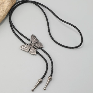 Detail of vintage silver butterfly bolo tie buckle with black braided faux leather cord