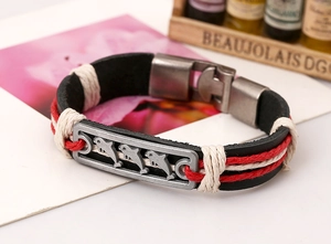 Detail of woven leather bracelet with antique silver metal plate featuring dolphin patterns