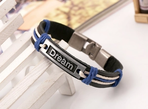 Detail view of Dream engraved metal plate on braided black leather and cord bracelet