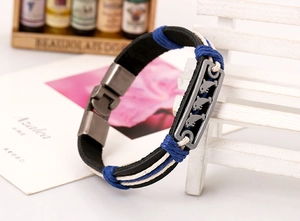 Macro detail of leather woven bracelet with engraved dolphin charm on wooden bench