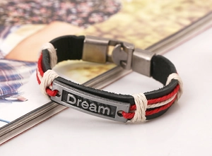 Detail of vintage braided leather bracelet featuring a silver Dream engraved metal plate
