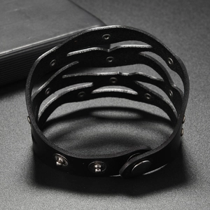 Détail d'un large bracelet punk en cuir noir avec rivets métalliques et bouton-pression