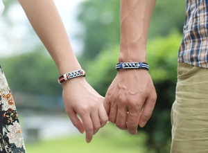 Macro shot of woven leather couple bracelets with engraved dolphin metal charms