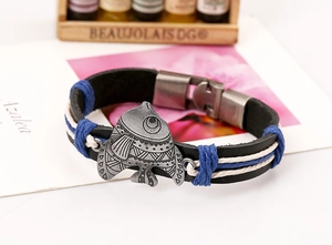 Nahaufnahme eines Vintage-Lederarmbands mit einem detaillierten Fisch-Anhänger aus Metall