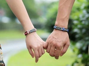 Close-up of Dream engraved metal plaques on woven leather bracelets for couples